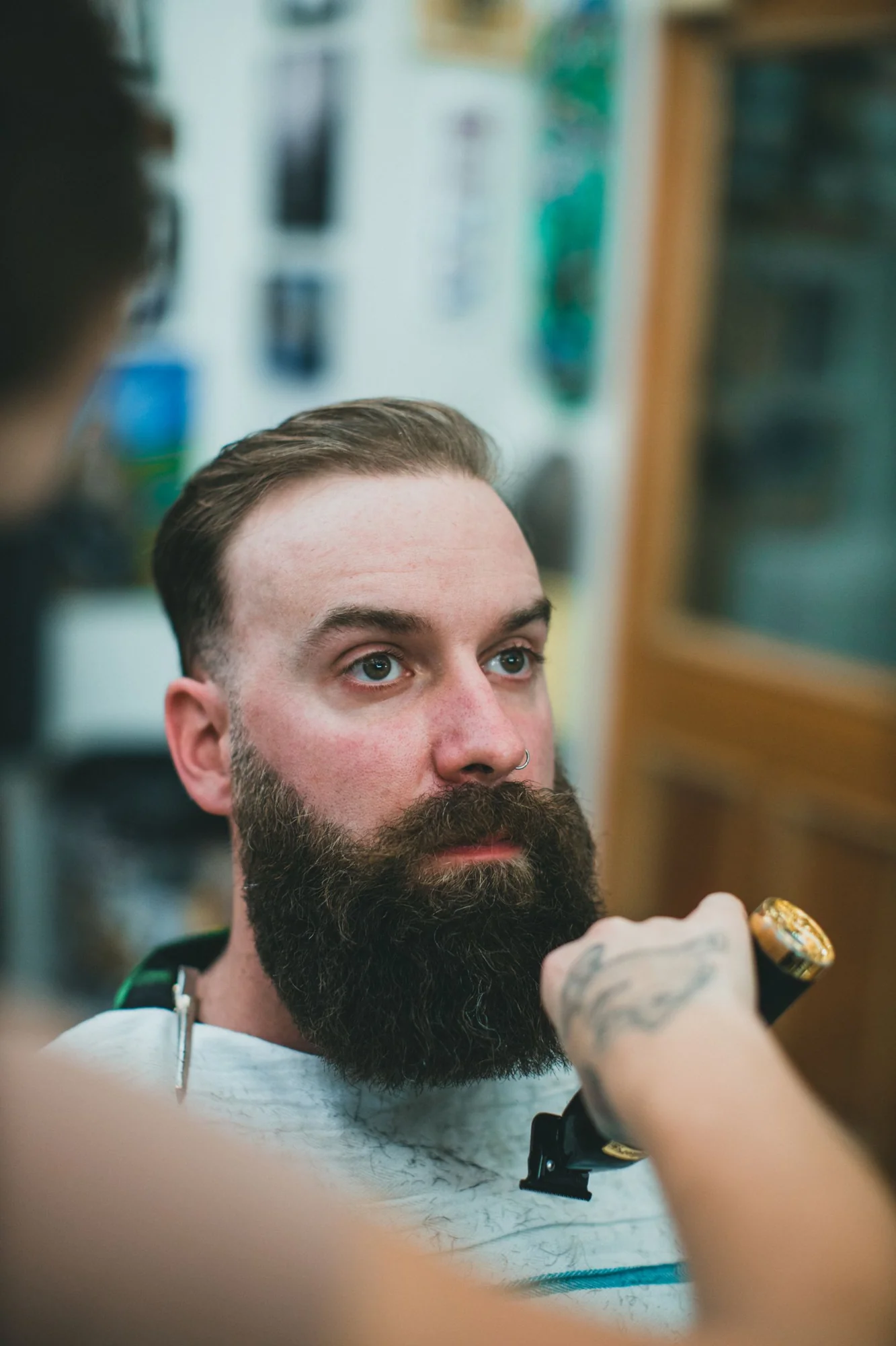 A barber carefully shaping a full beard
