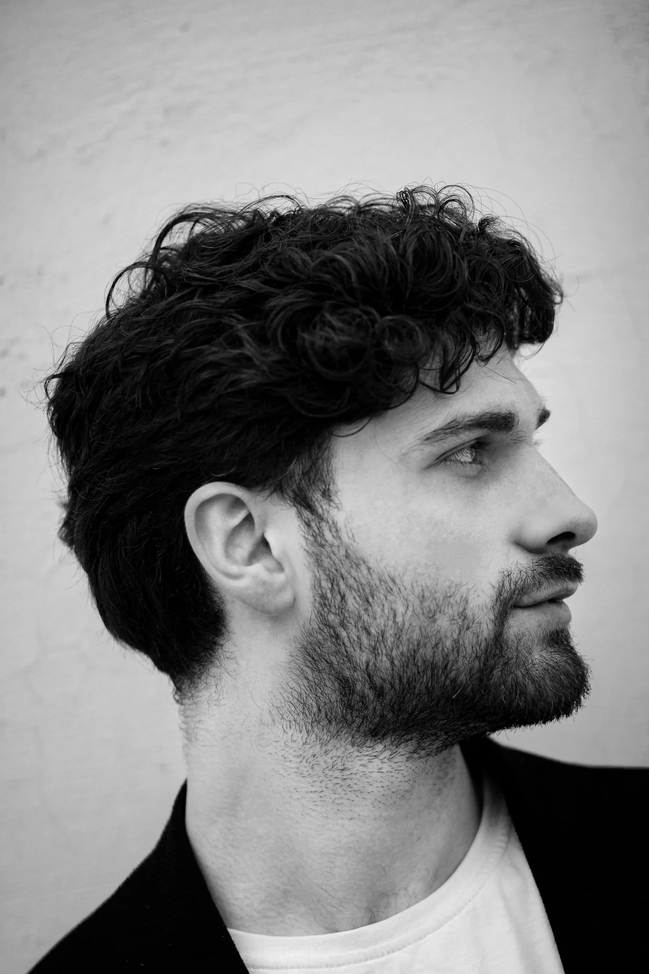 Black-and-white side-profile portrait showing natural waves and a short beard