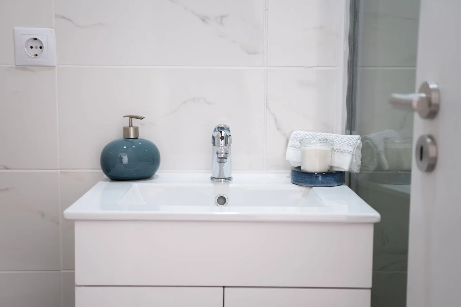 White bathroom vanity with chrome faucet and teal detail