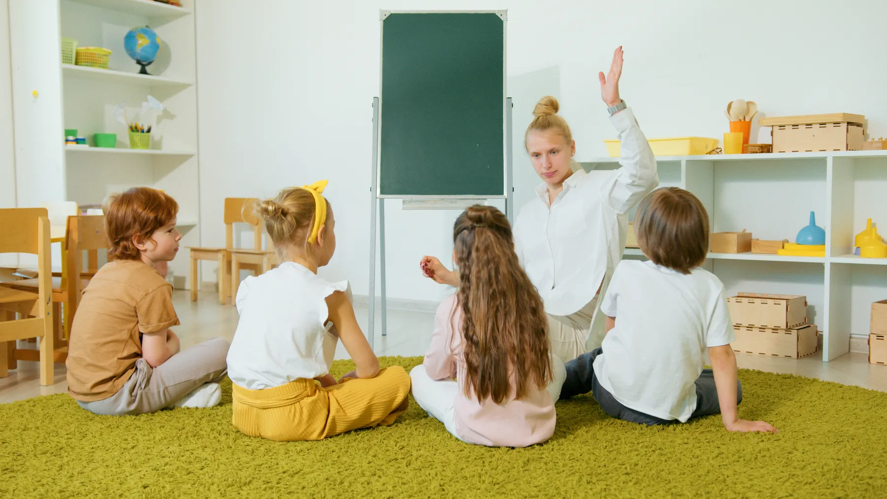 Children seated in a classroom circle with an adult leading an activity