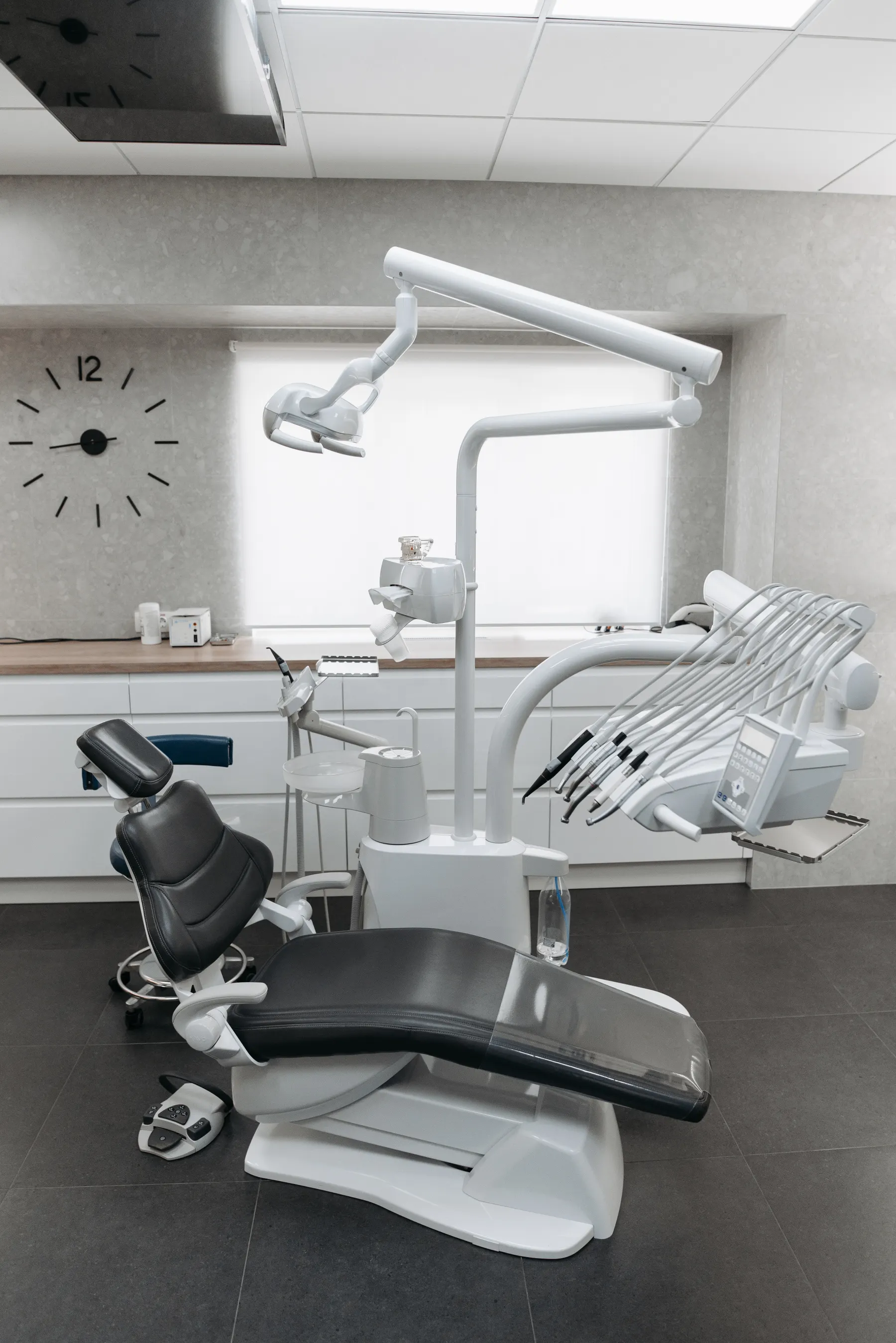 Airy dental room with a black treatment chair and white instruments