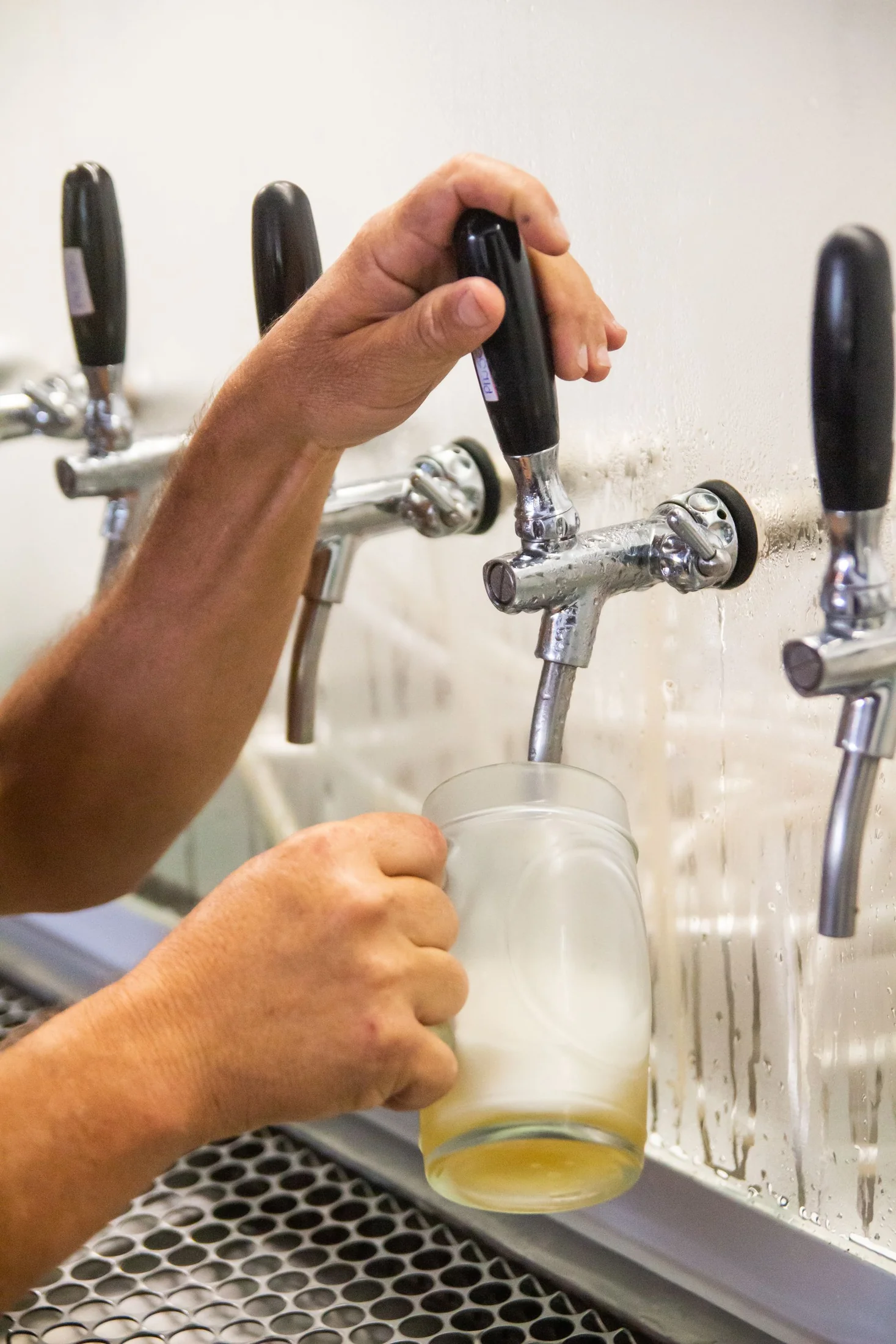 A hand operating a chrome draft tap