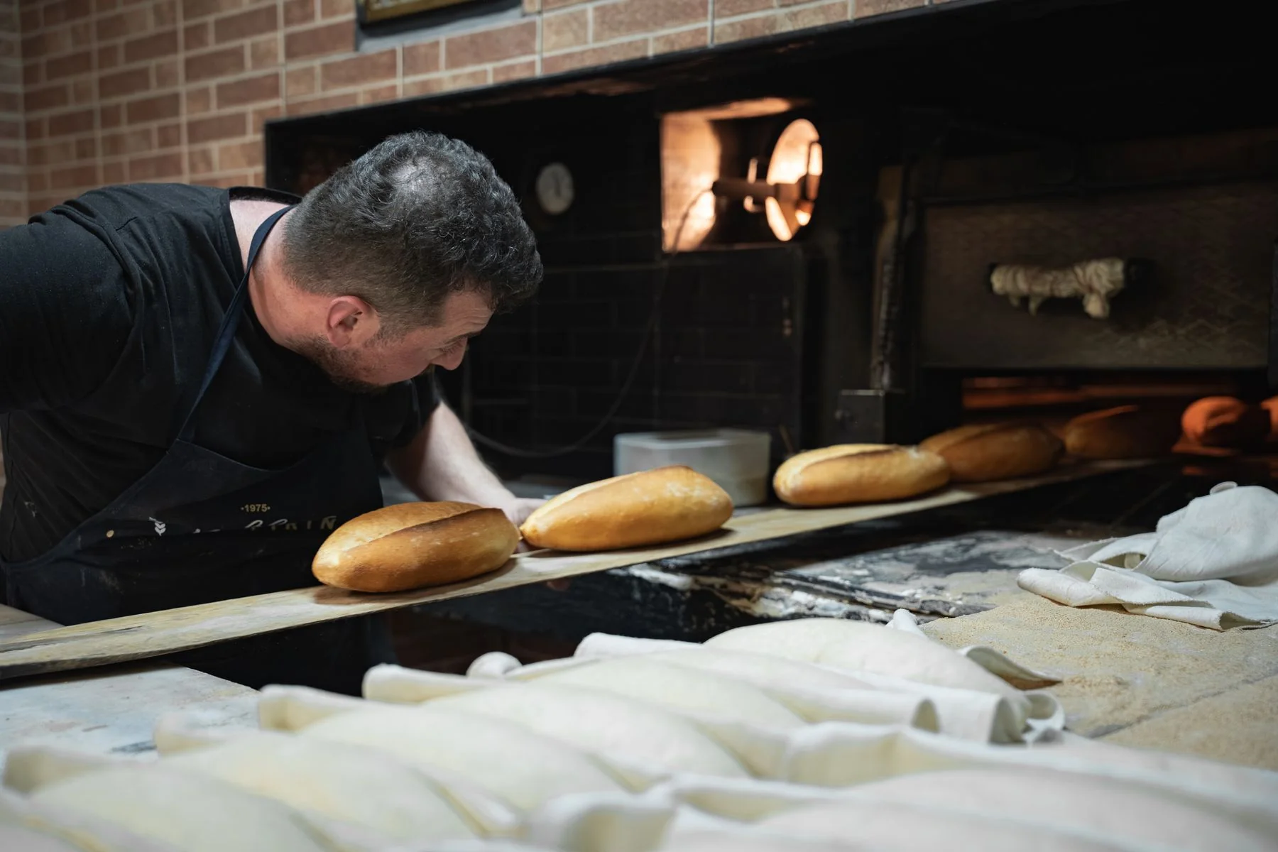 A baker preparing bread beside an oven
