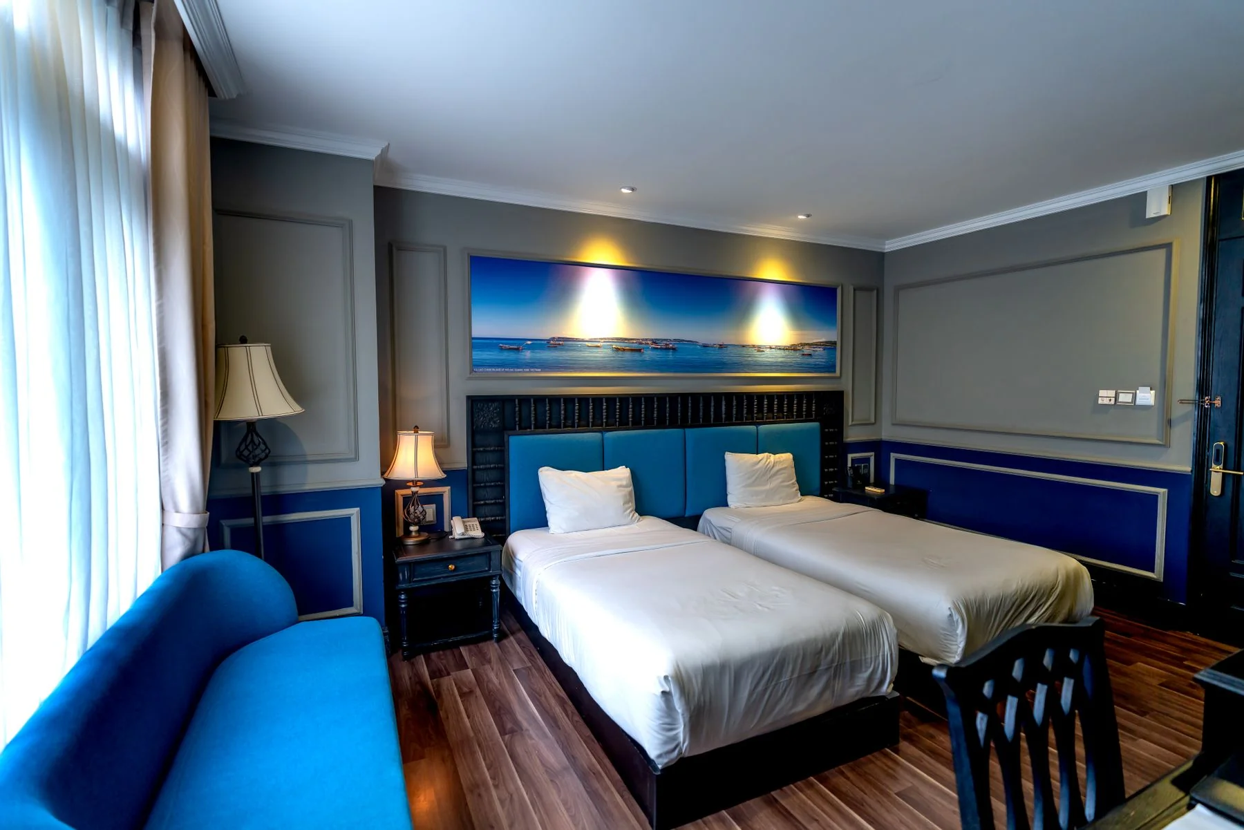 Twin beds and a blue sofa in a hotel room