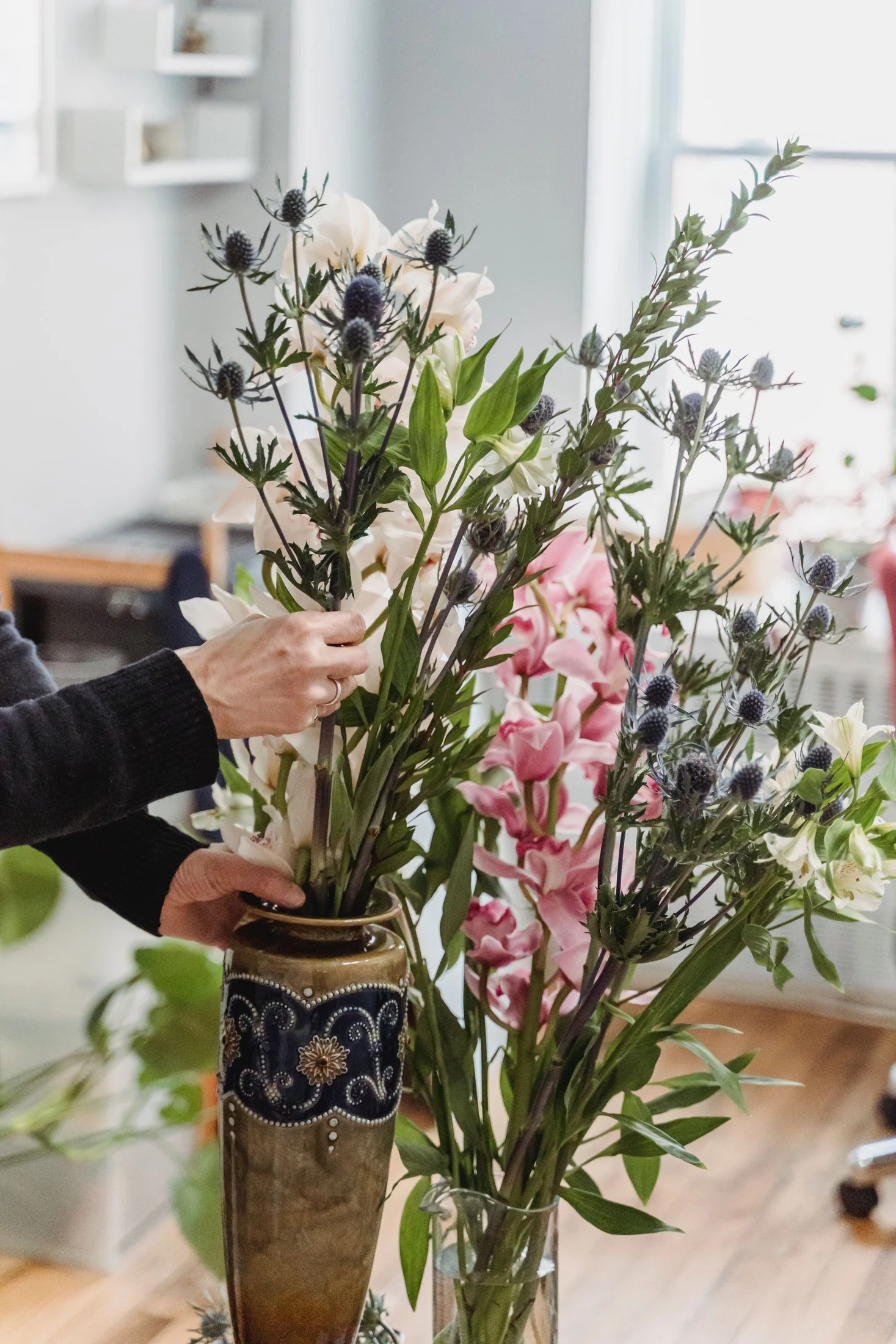 Hands arranging flowers in a ceramic vase