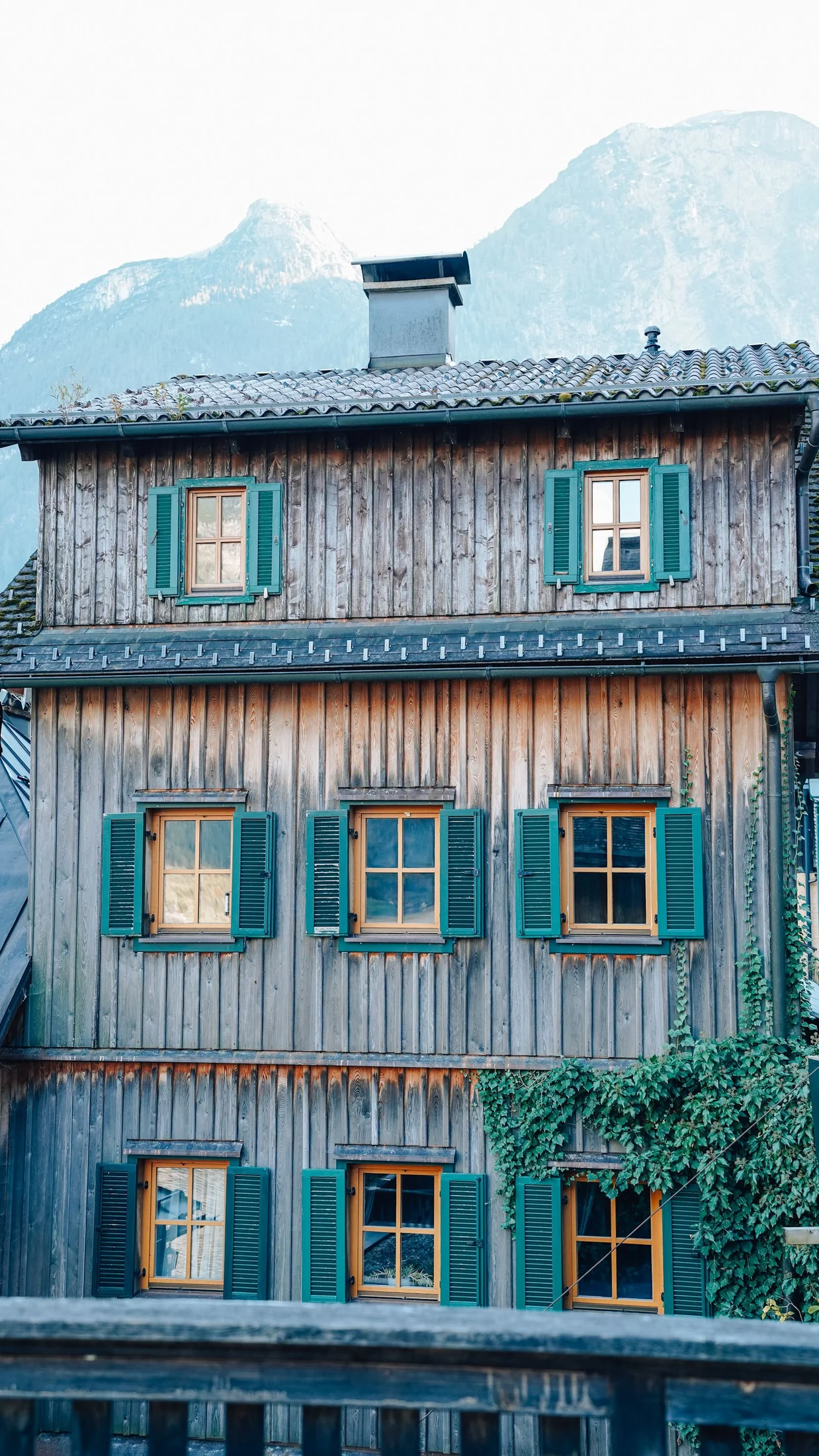 A timber lodge with green shutters and mountains behind