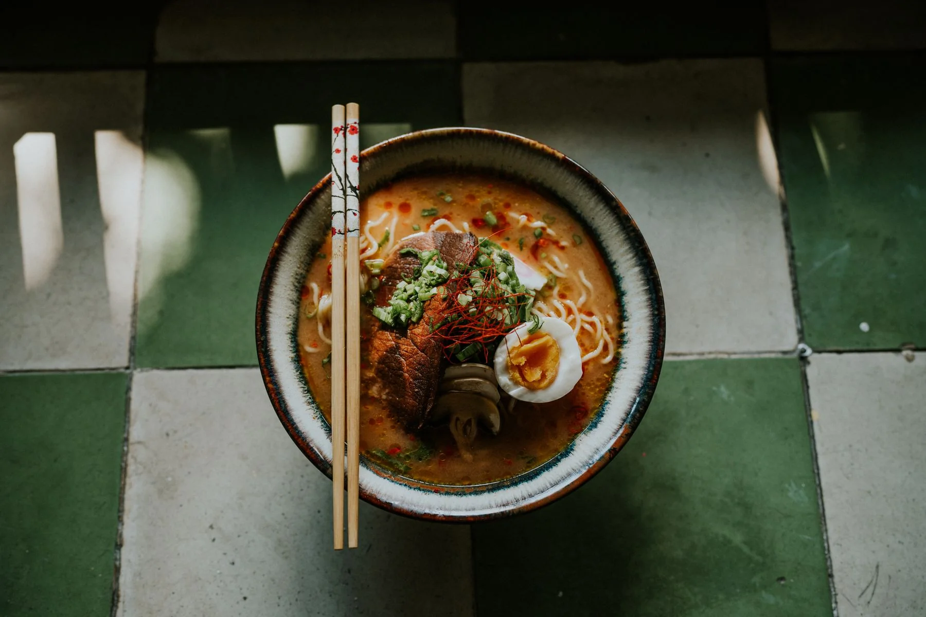 A bowl of ramen with noodles, egg and scallions