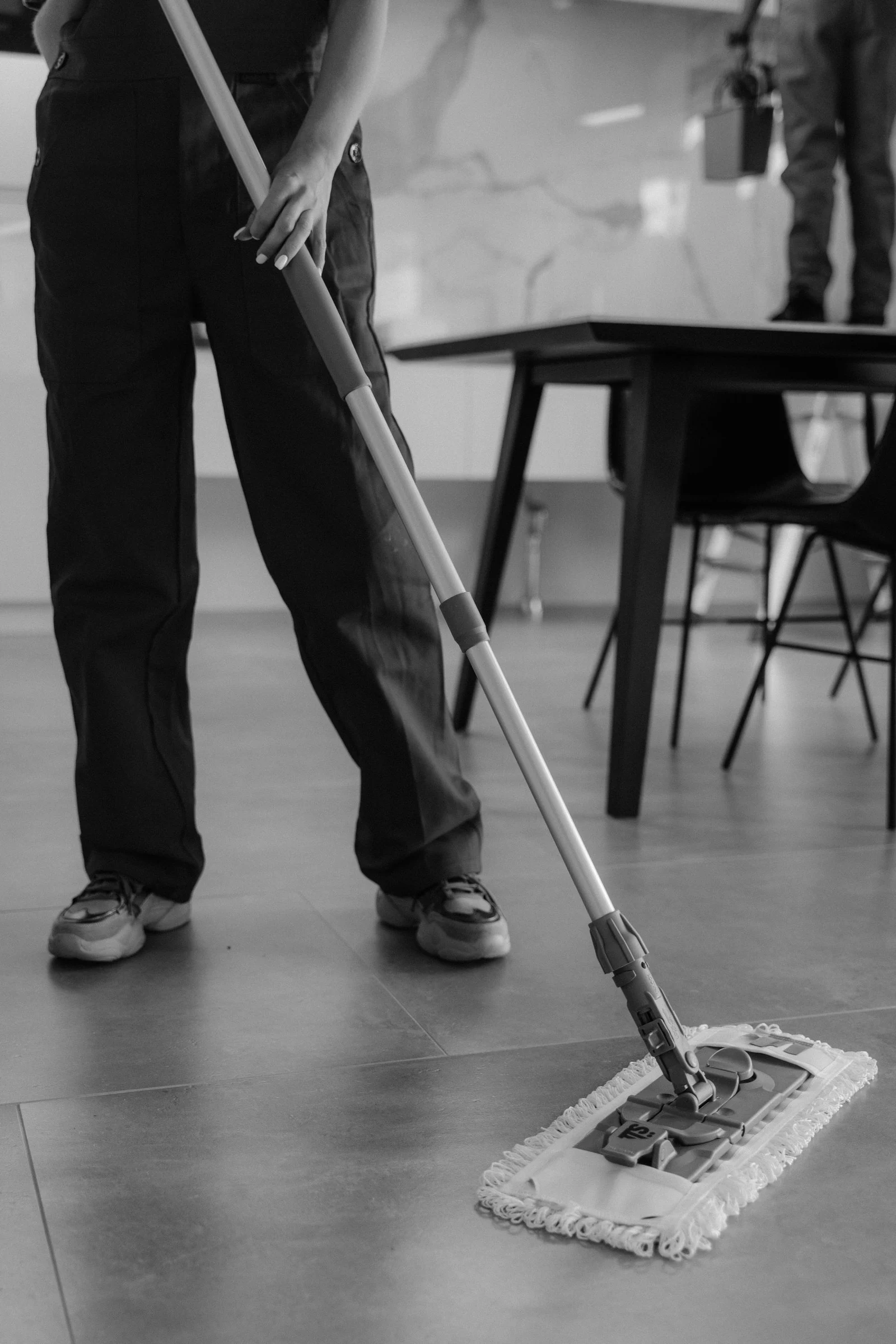 Monochrome photograph of a person mopping an interior floor