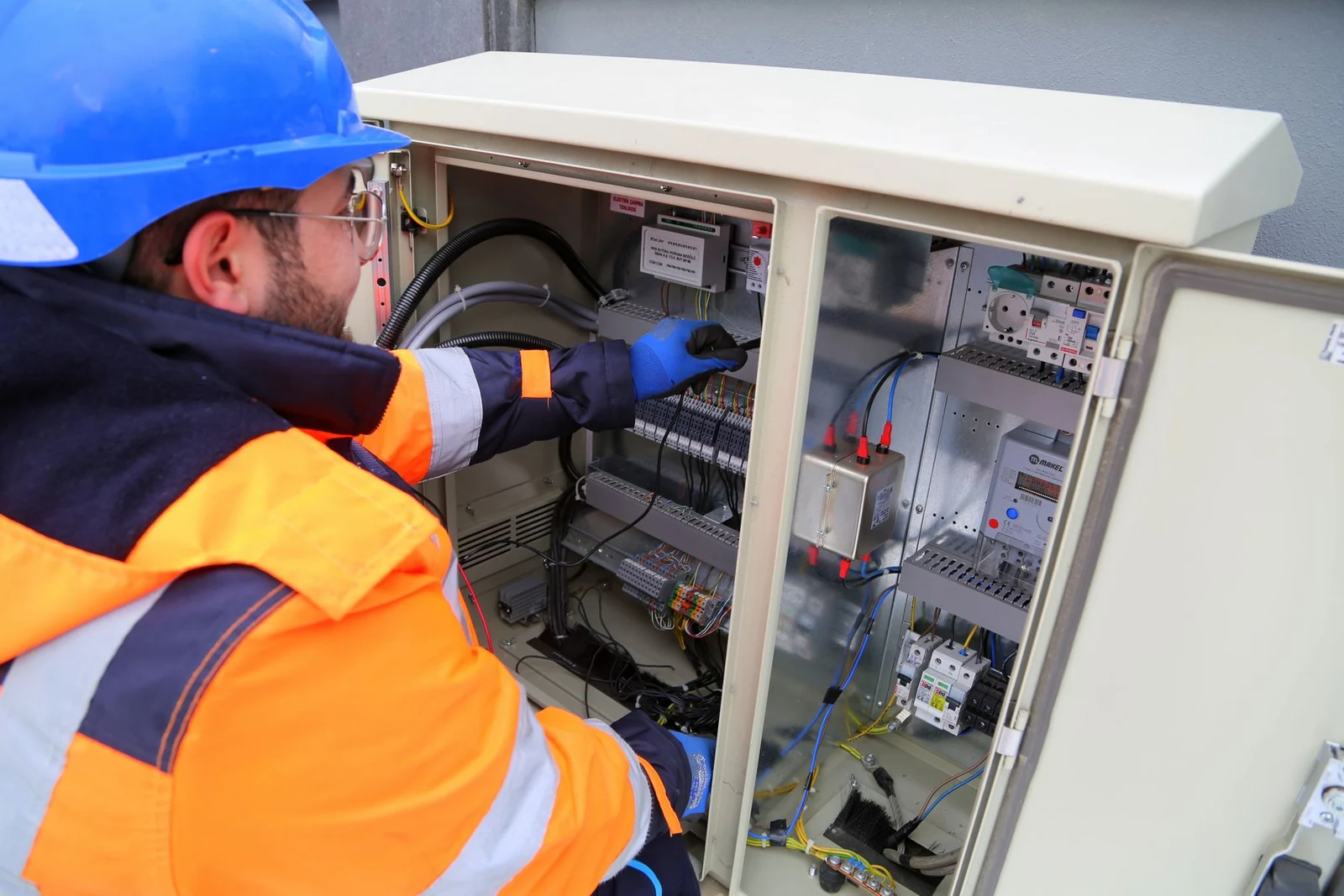 Technician in safety clothing working on an electrical service panel