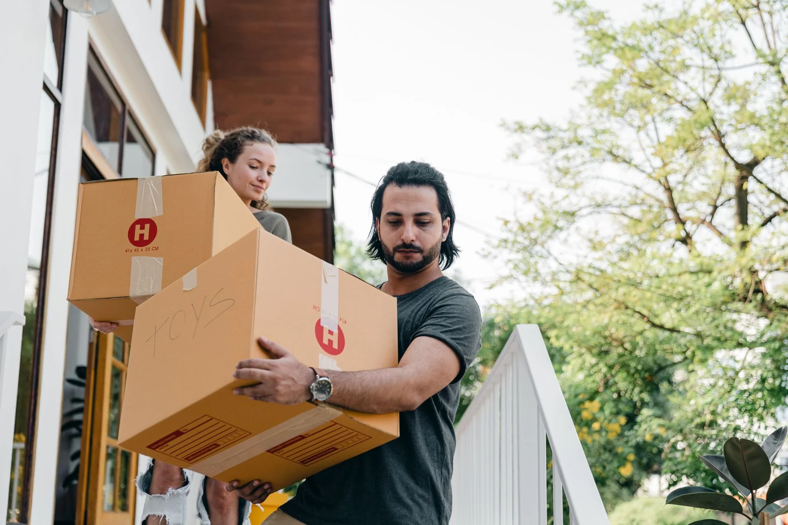 Two people carrying cartons down exterior steps
