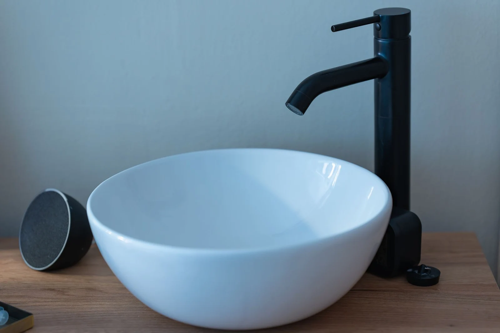 White vessel basin and black faucet on a wooden vanity