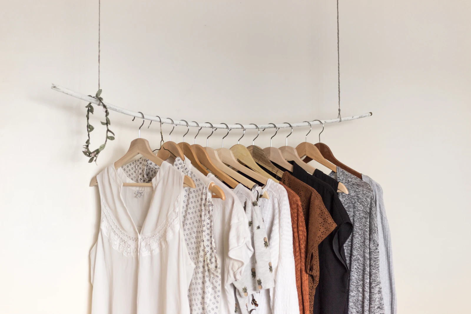 An edited rail of soft neutral clothing on wooden hangers